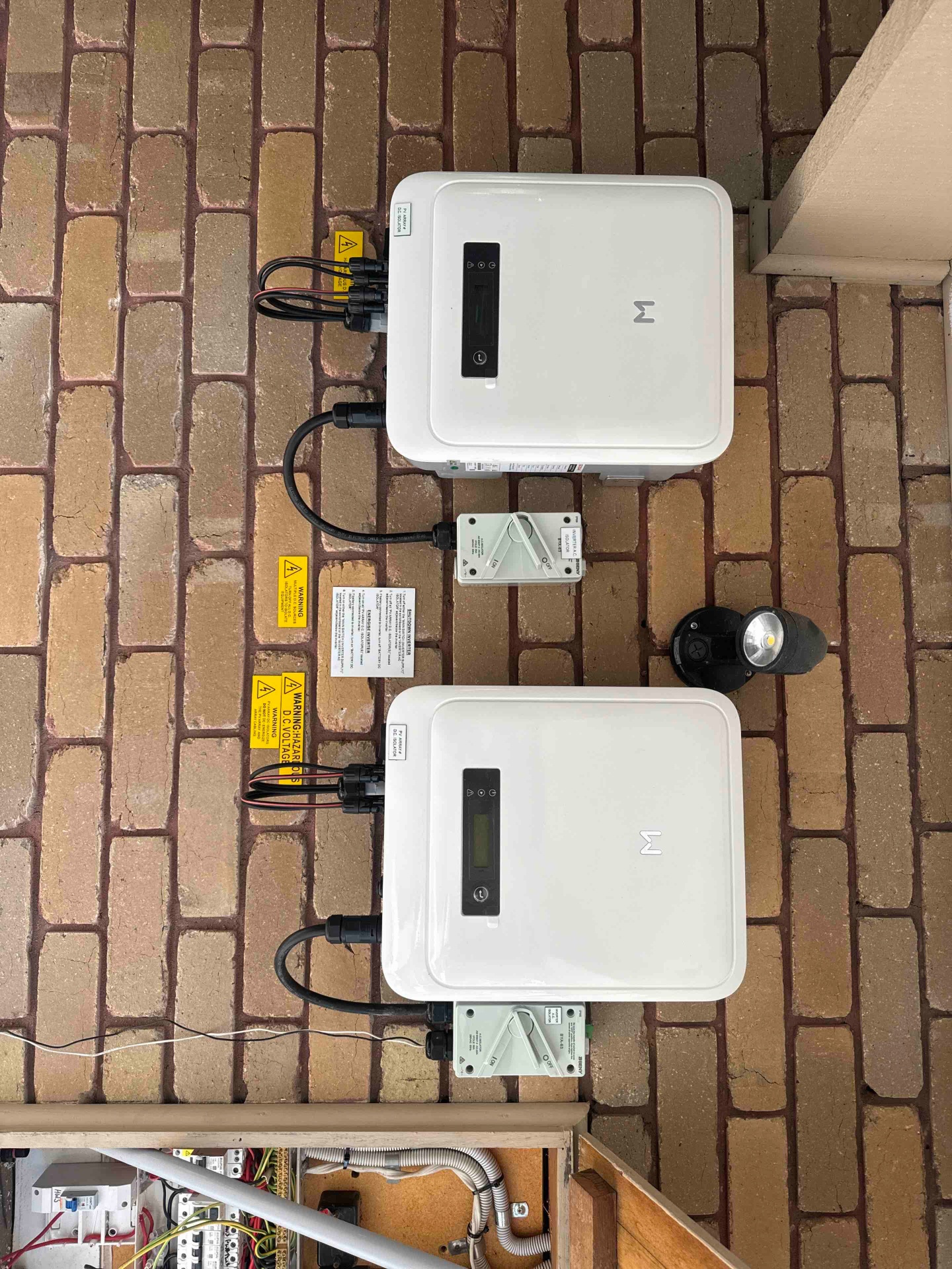 Dual white inverters mounted on brick wall